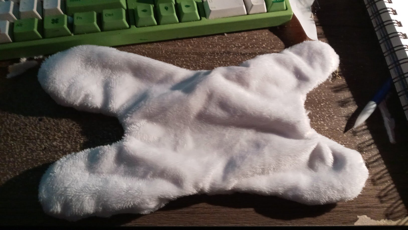 the body of the dogthing laid flat with no stuffing on particle-board table. it resembles a sideways H shape.